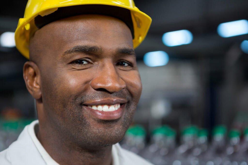 close up portrait of smiling male worker wearing hard hat in warehouse